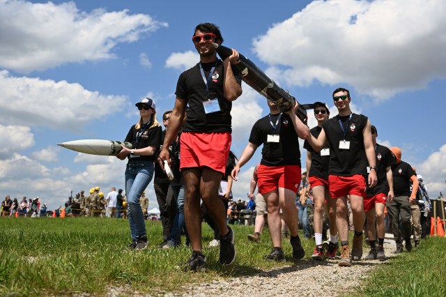 Happy Student Launch participants carry their rockets.