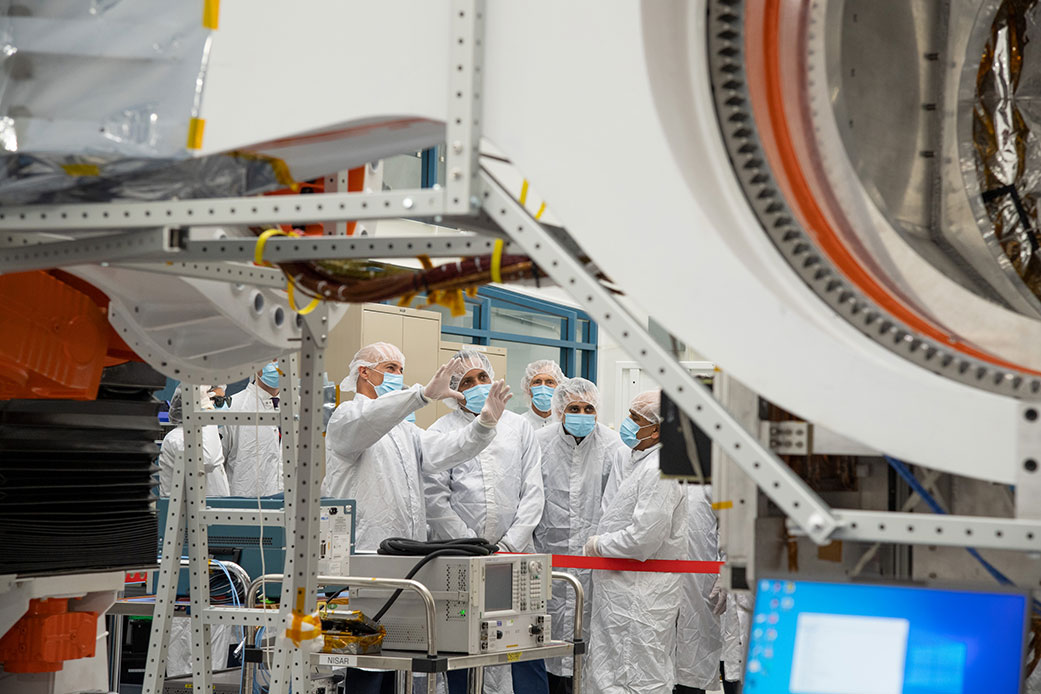 NASA’s NISAR Project Manager Phil Barela speaks in a JPL clean room with ISRO Chairman S. Somanath and other officials