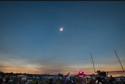 Photo of an bright eclipse in a twilight sky above a crowd of people