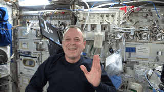 Flight Engineer Ricky Arnold waves as he explains the importance of solar energy on the space station