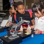Young students look at a model of a robotic arm