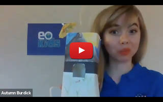 A woman holds a birdhouse made from a milk carton