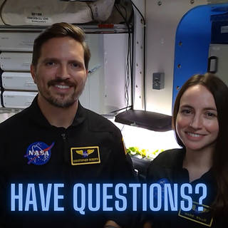 Crew members Christopher Roberts and Madelyne Willis pose inside the HERA habitat with the title “Have Questions?”