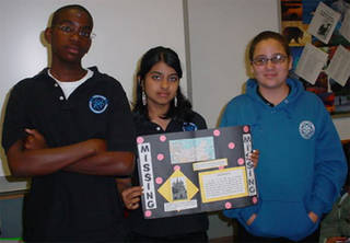 Three students holding up a sign