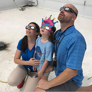 A family wearing eclipse glasses watches the total solar eclipse on Aug. 21, 2017