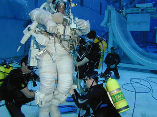 An astronaut trains in the NBL and is assisted by professional scuba divers