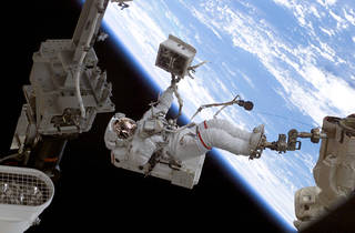 An astronaut on the robotic arm of the ISS