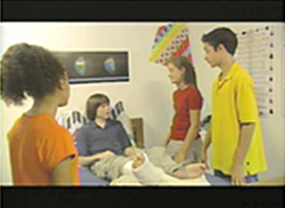 Three students visit a boy in bed with a cast on his leg