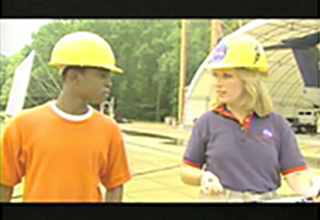 A student in a hard hat talks with a woman wearing a hard hat