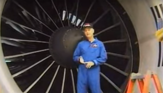 A man stands in front of a large airplane engine