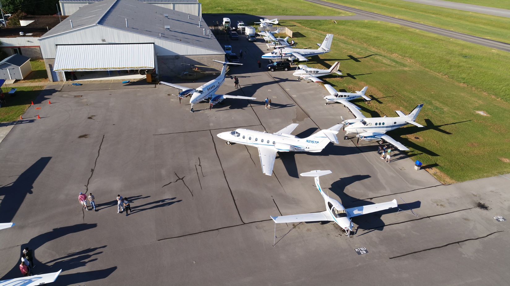 A group of airplanes pointing in various directions sits on the tarmac of an airport near a large building.