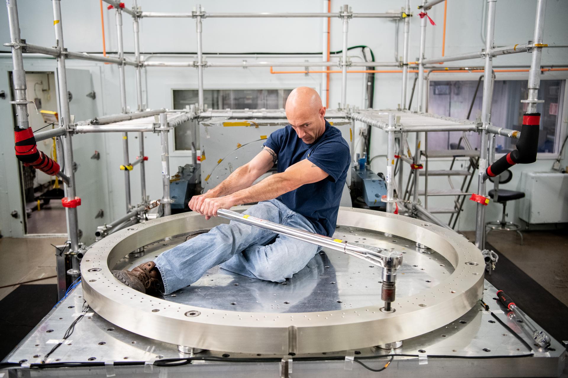 Engineering Technician torques the Force Gauge Ring on to the vibe table in preparation for vibration testing