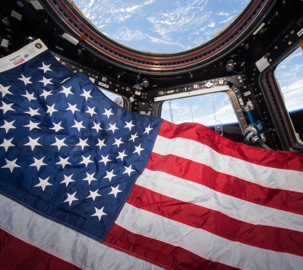 an American flag onboard a space flight with earth visible through the aircraft's window