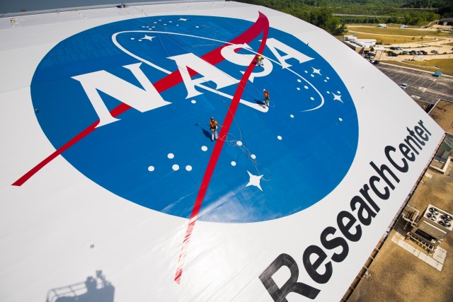 People painting NASA logo on hangar roof.