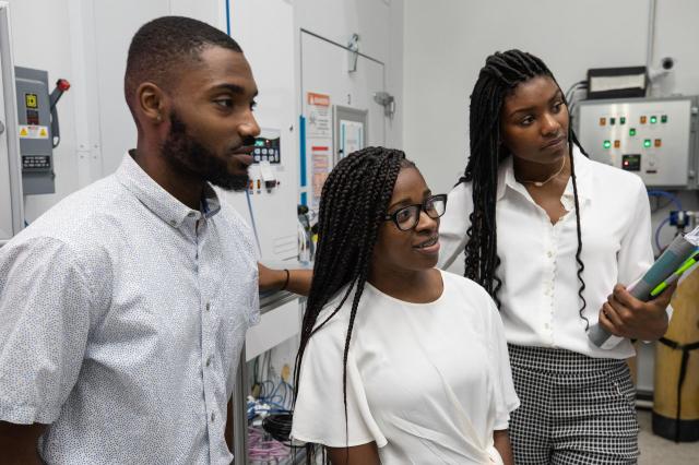 3 students in a lab looking at something outside of the picture.