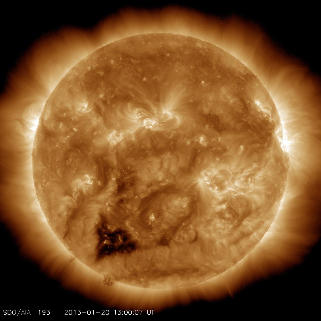 An ultraviolet view of the Sun, which appears as a peach-colored, glowing ball with soft rays shining around its circumference. In addition to brighter and darker swirls of light on the Sun's surface, a small dark area in its lower left is shaped slightly like a heart.