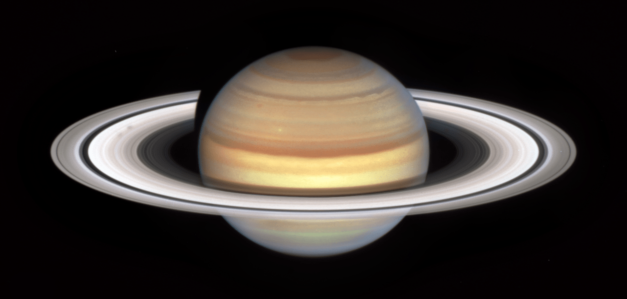 Saturn and its rings fill the view. Saturn has yellow, reddish-brown, and tan stripes. Saturn's rings are tilted slightly, allowing us to see ring bands along with the wide dark band called the Cassini Division.