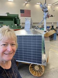 Carol Carroll poses with a full-scale model of NASA’s next Moon rover