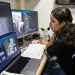 A woman works in front of multiple computer screens