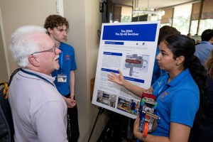 Two Micro-g NExT participants present their poster to a NASA employee