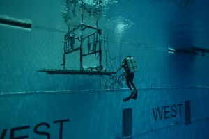 Underwater diver in the Neutral Buoyancy Lab approaching a metal apparatus
