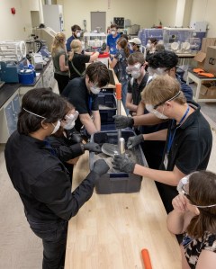 A group of Micro-g NExT participants testing a space tool in a bucket of space dirt.