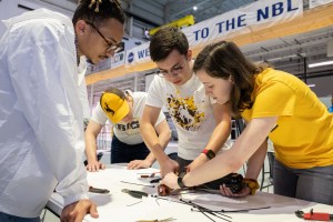 A group of 4 Micro-g NExT participants work on their space tool prototype at a table