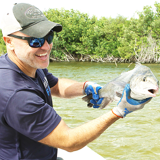 Biologists Eric Reyier, PhD holding a fish