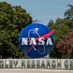 Sign with three-dimensional NASA insignia and text reading Langley Research Center with trees in background