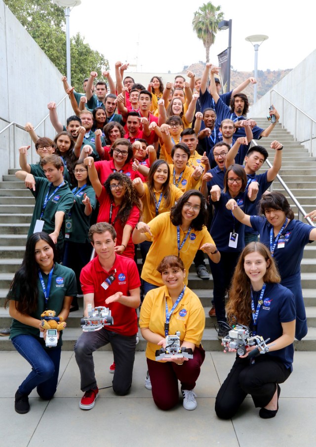 Group photo of students standing on a staircase holding small rovers