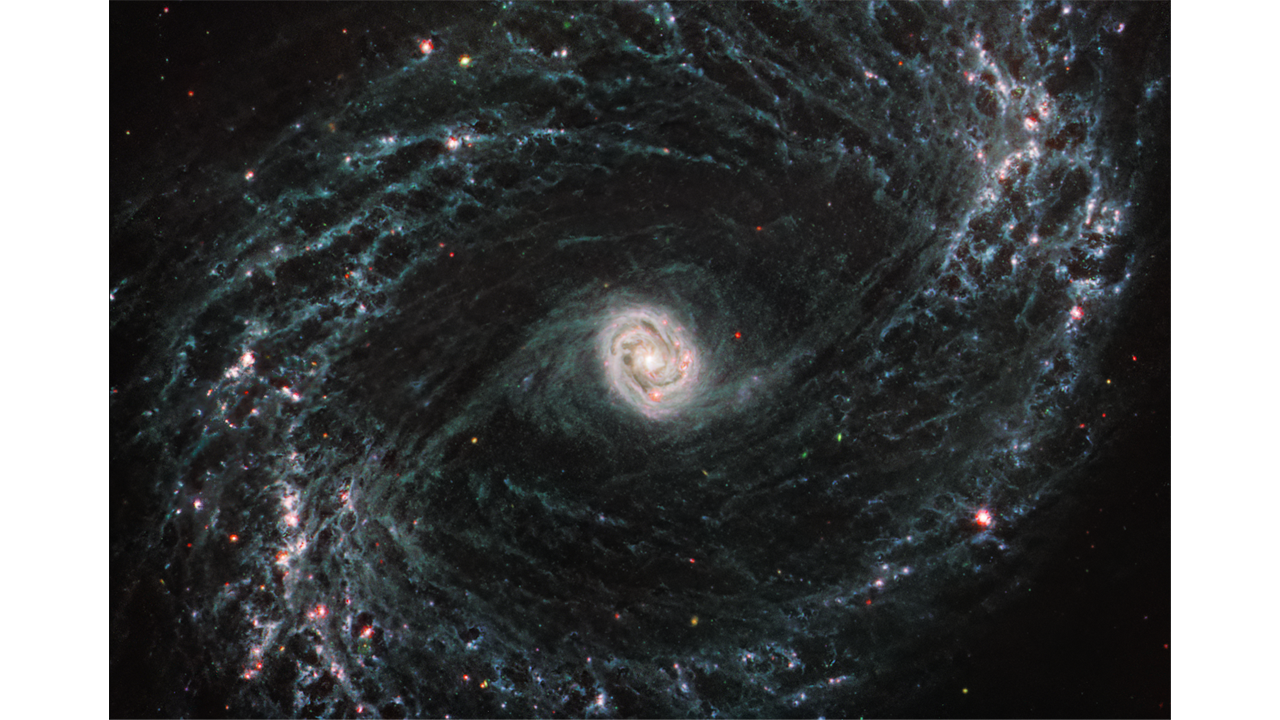 A galaxy spiral with a bright, white center. At the top right and lower left are brighter spots of red, with light blue web like spirals throughout.
