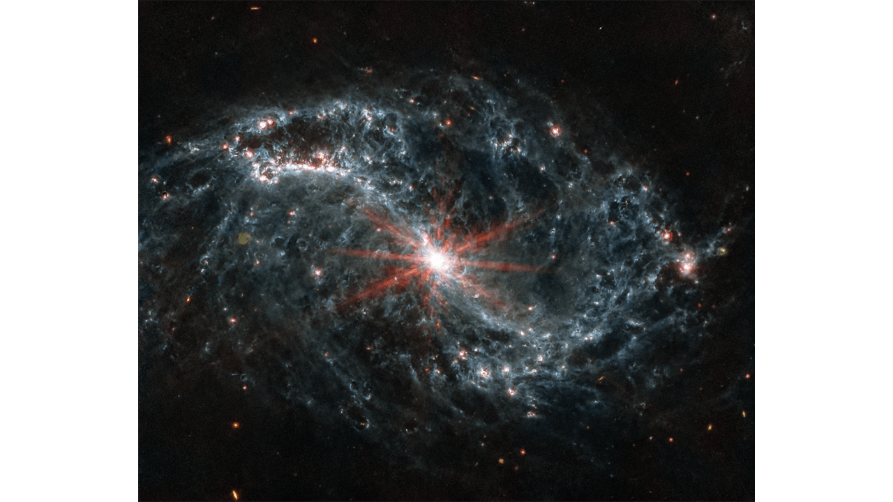 A galaxy spiral with a bright, star-like burst red center with light blue web like spirals throughout.