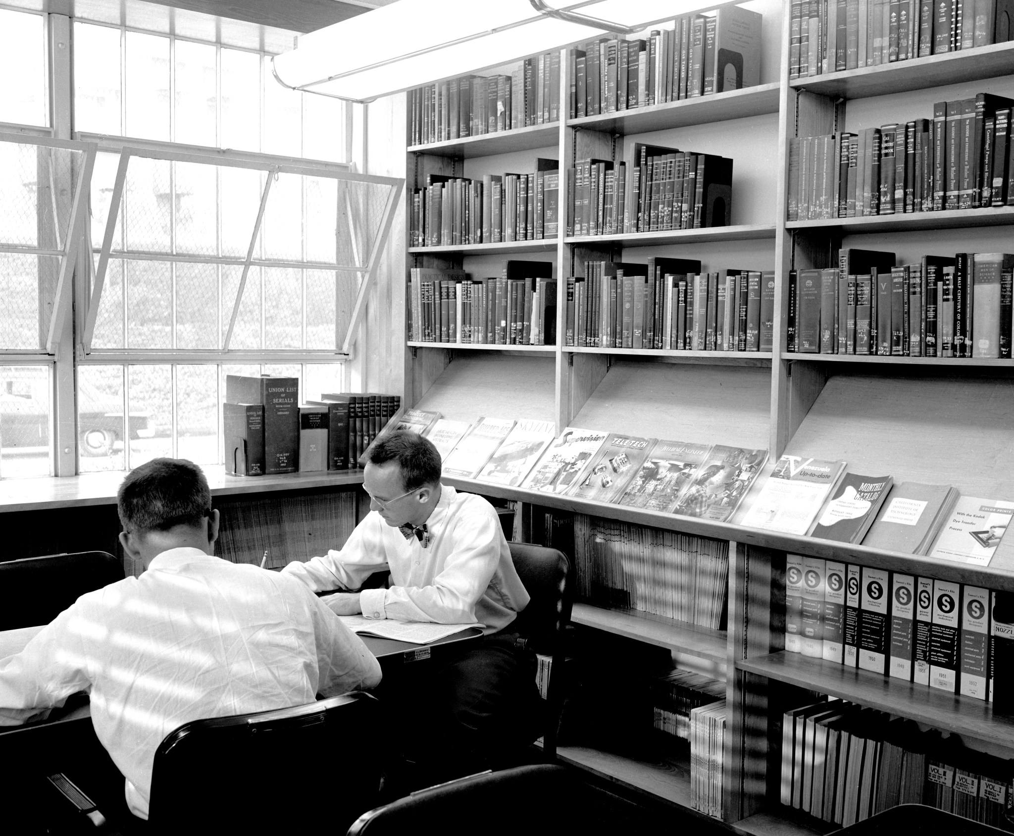 Two men study in the JPL Library. 