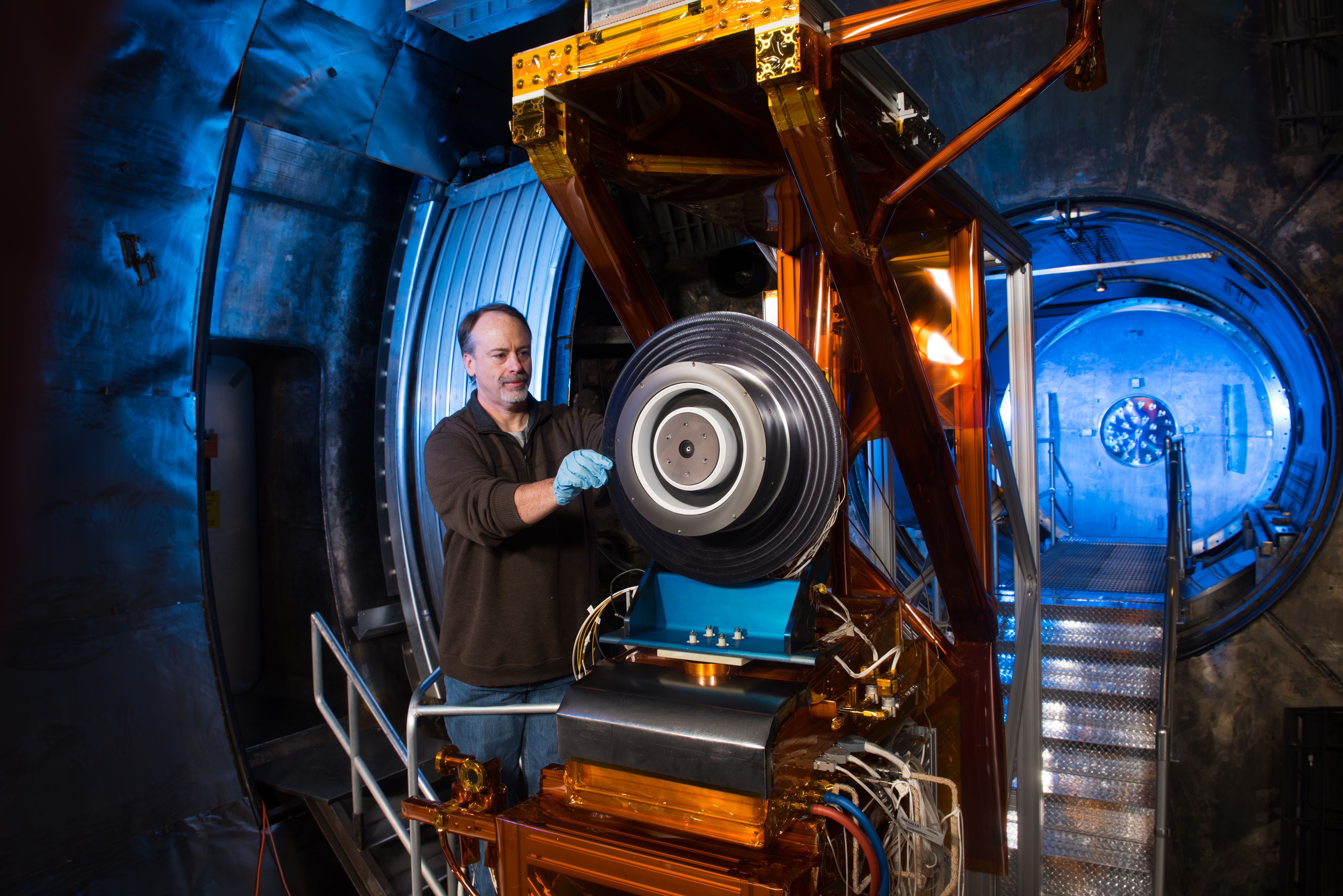 NASA engineer prepares a high-power Hall thruster for ground testing in a vacuum chamber.
