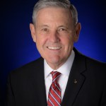 A man in a blue suit with a white shirt and red tie.