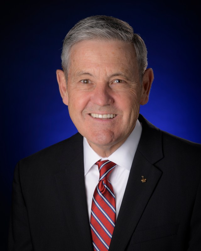A man in a blue suit with a white shirt and red tie.