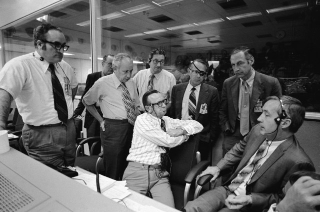 NASA officials gather around a console in the Mission Operations Control Room during Apollo 16. Seated, center to right, are Manned Spacecraft Center (MSC) Director Chris Kraft, and Apollo Spacecraft Program Office Manager James McDivitt. Standing, left to right, Apollo Program Director Rocco Petrone, Apollo Operations Director John Holcomb, MSC Deputy Director Sig Sjoberg, Apollo Mission Director Chester Lee, NASA Associate Administrator for Manned Space Flight Dale D. Myers, and NASA Deputy Administrator George Low. (20 April 1972)