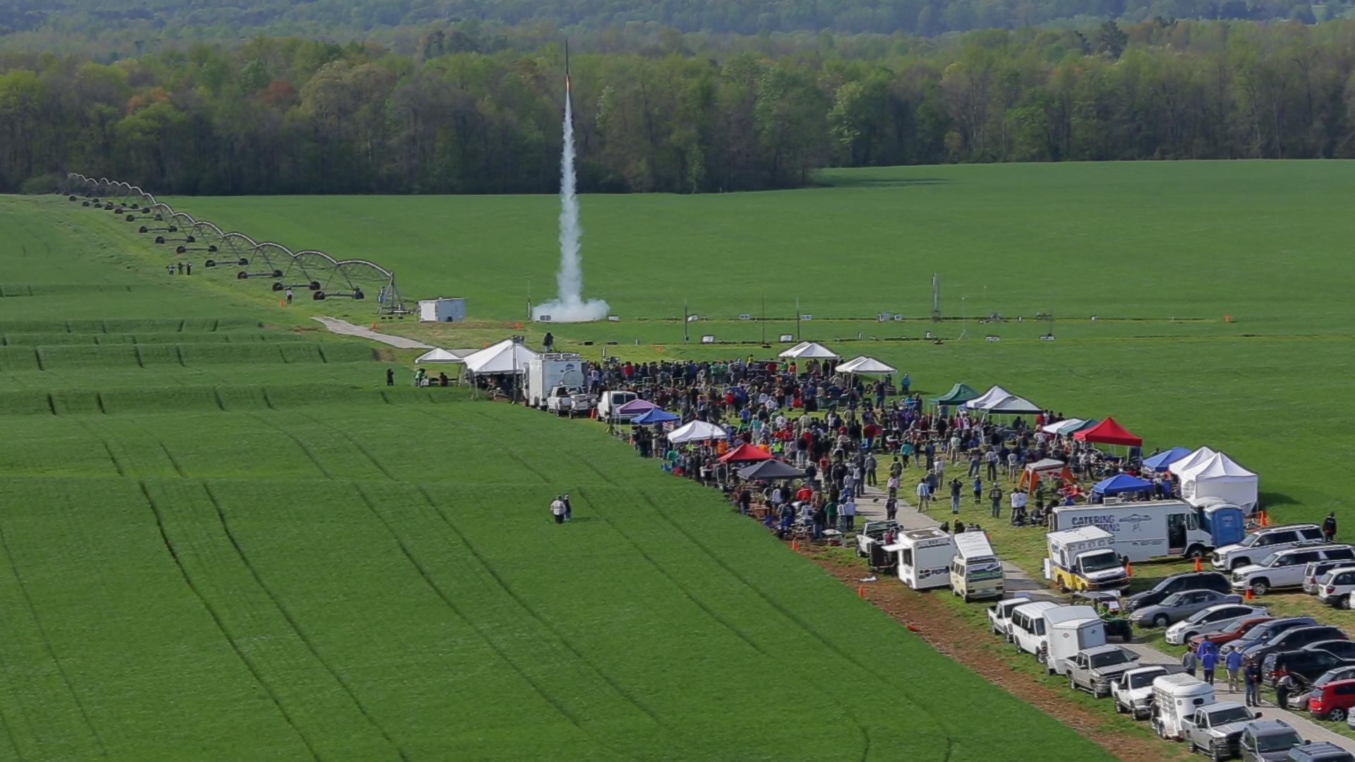 A patch of green field as a rocket from the student launch competition rises in the sky.