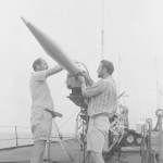 Two men set up a rocket on a mobile launcher.