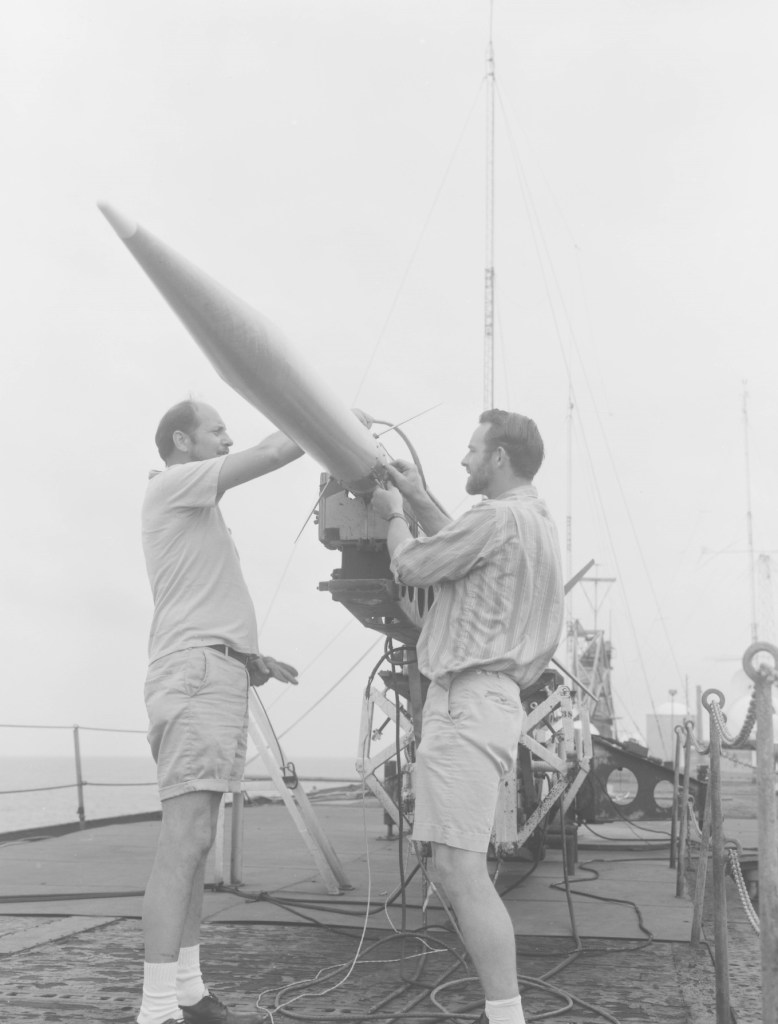 Two men set up a rocket on a mobile launcher.