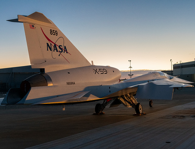 NASA’s X-59 quiet supersonic research aircraft sits on the ramp at Lockheed Martin Skunk Works in Palmdale, California during sunrise, shortly after completion of painting. With its unique design, including a 38-foot-long nose, the X-59 was built to demonstrate the ability to fly supersonic, or faster than the speed of sound, while reducing the typically loud sonic boom produced by aircraft at such speeds to a quieter sonic “thump”. The X-59 is the centerpiece of NASA’s Quesst mission, which seeks to solve one of the major barriers to supersonic flight over land, currently banned in the United States, by making sonic booms quieter.