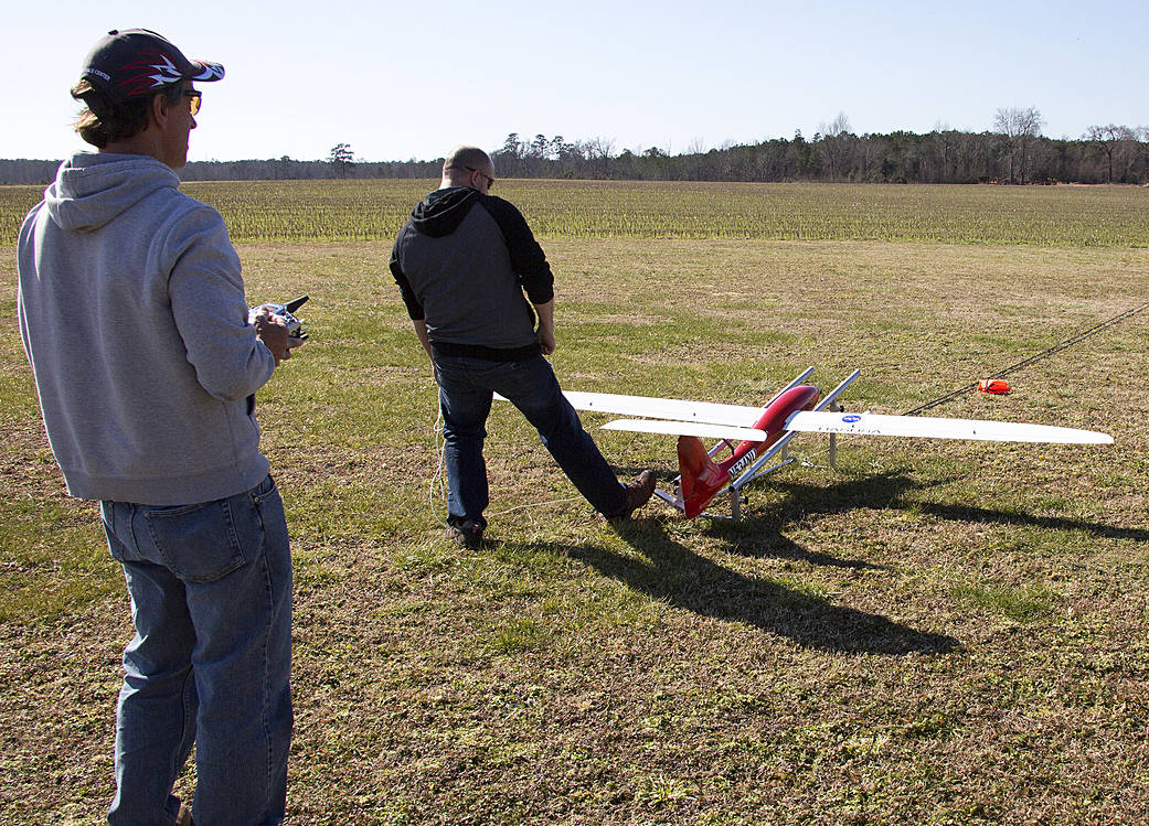 Researchers work with a Tempest plane out in a field.
