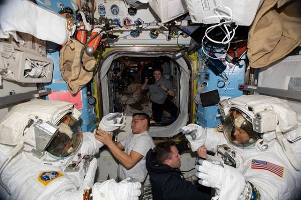 image of astronauts preparing for a spacewalk inside the airlock aboard the space station