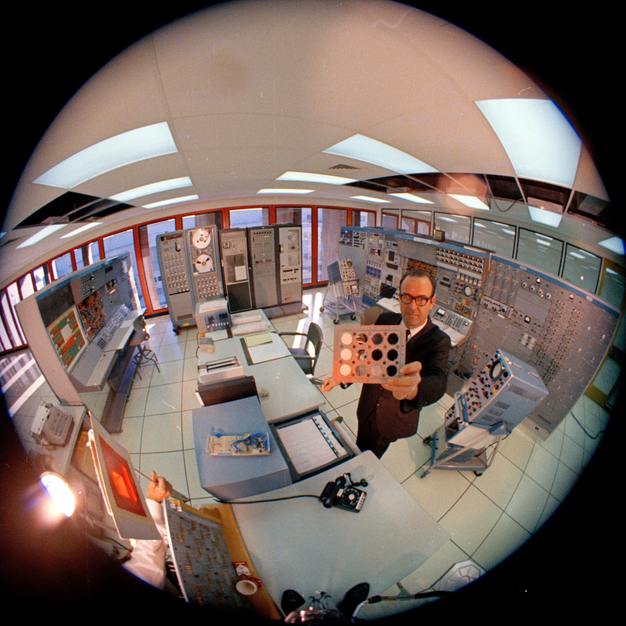 Photograph of engineer, George Holden in a computer room at Ames Research Center holding up an experimental board.