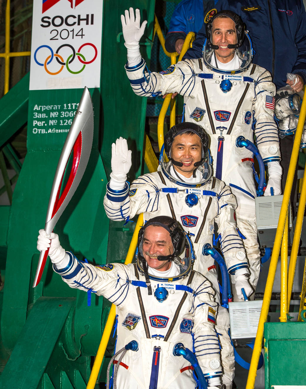 Expedition 38 Soyuz Commander Mikhail Tyurin of Roscosmos, holding the Olympic torch, Flight Engineer Koichi Wakata of the Japan