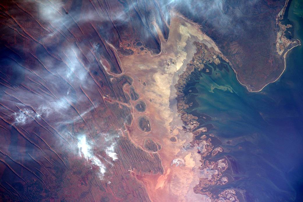 Coast of Australia with clouds overhead and colorful streaked terrain