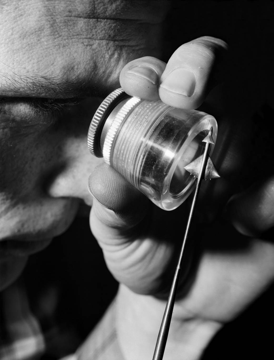 Very close in photograph of man peering through glass at tiny aircraft model