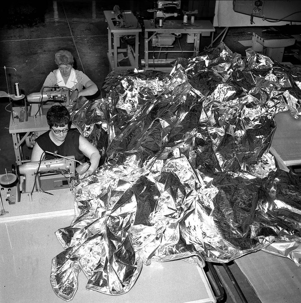 A parasol sunshade being stitched together by two seamstresses at NASA's Marshall Space Flight Center.