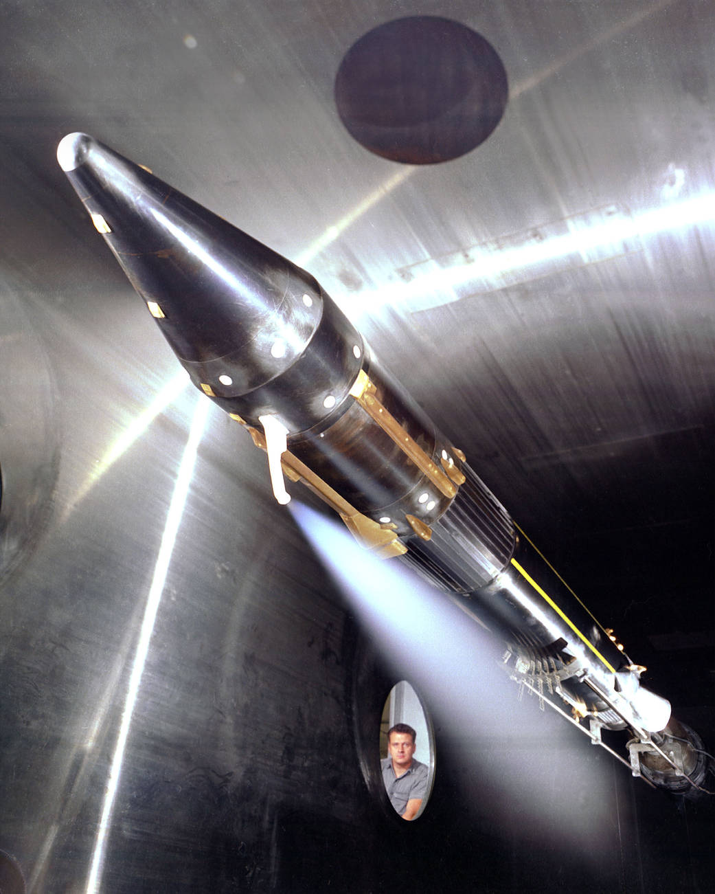 Large silver rocket model in wind tunnel pointed diagonally upward
