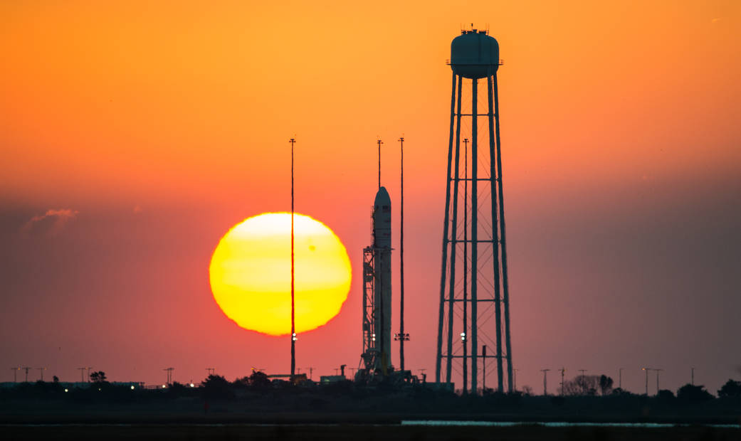 The Orbital Sciences Corporation Antares rocket, with the Cygnus spacecraft at launch pad with sun rising in the background